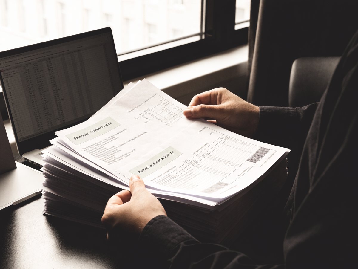 Reconciled supplier invoices being worked through beside a spreadsheet